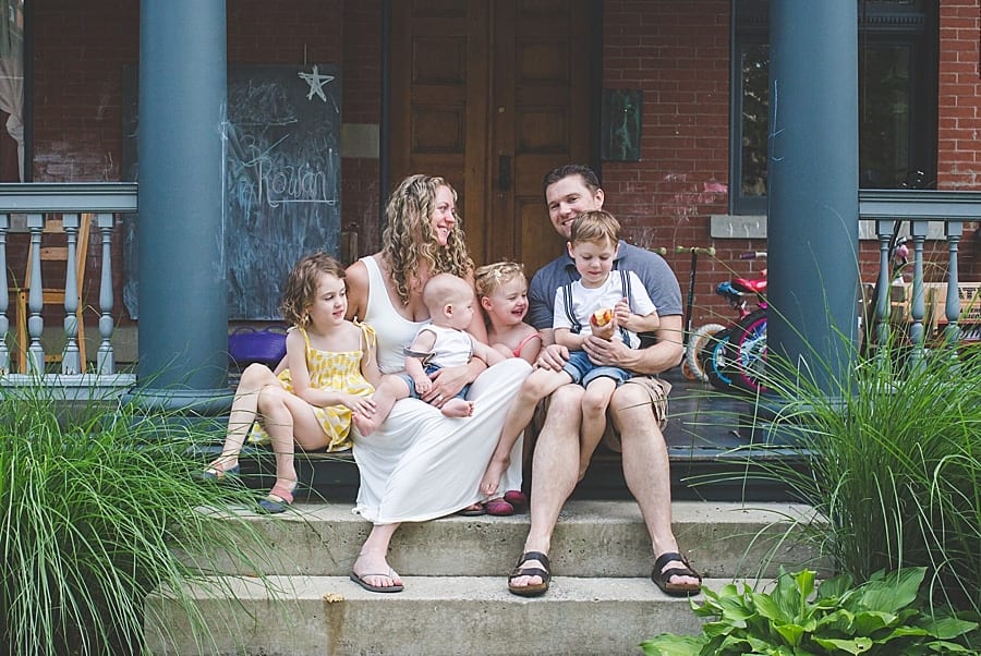 mom dad and four children sitting on the porch stoop of their home  Boardman family photographer 