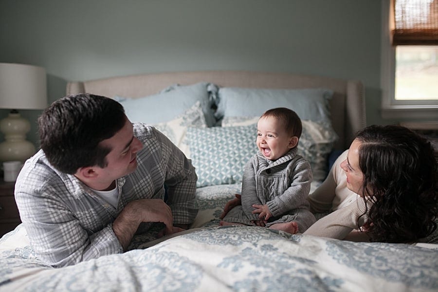 mom and dad with baby on bed inside their Poland ohio home for a lifestyle family photo session