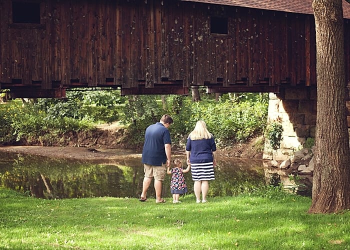 family holding hands for a photo session in front of covered bridge at brush creek locations for photo sessions in beaver county