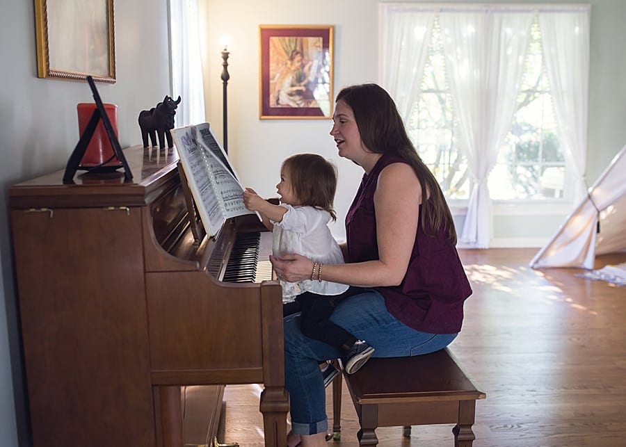 mom and toddler at piano with windows behind them for a photo session in their home