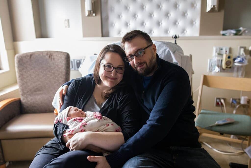 mother and father on hospital bed holding newborn daughter  tips to taking your own fresh 48 photos