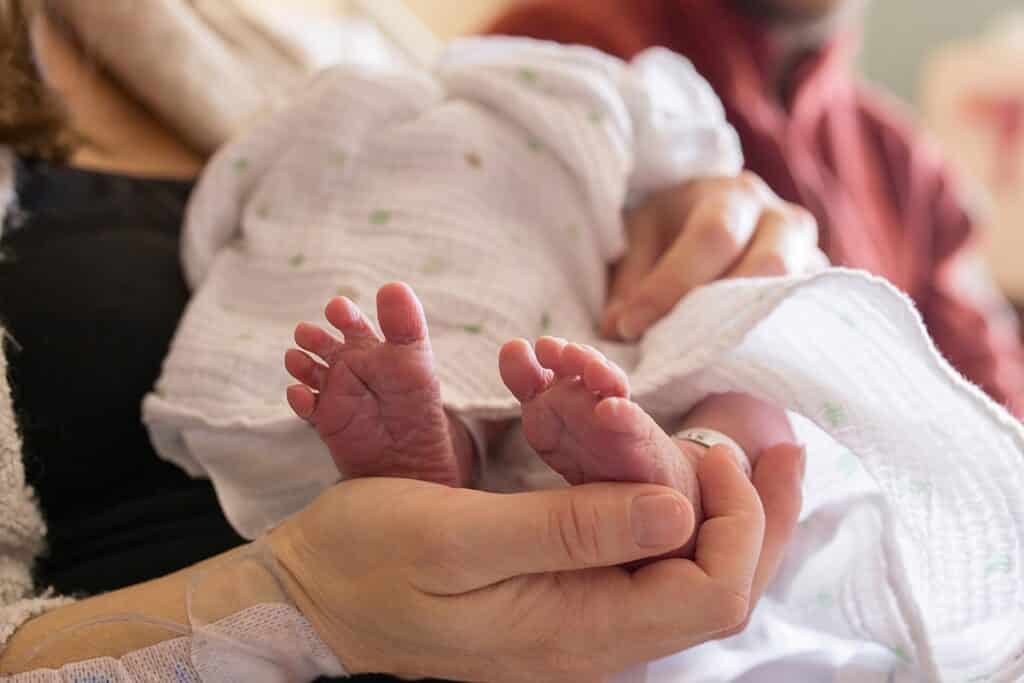 newborn baby feet in moms hands in hospital 
