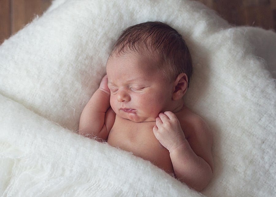 newborn baby sleeping on white fuzzy blanket for a canfield newborn photo session