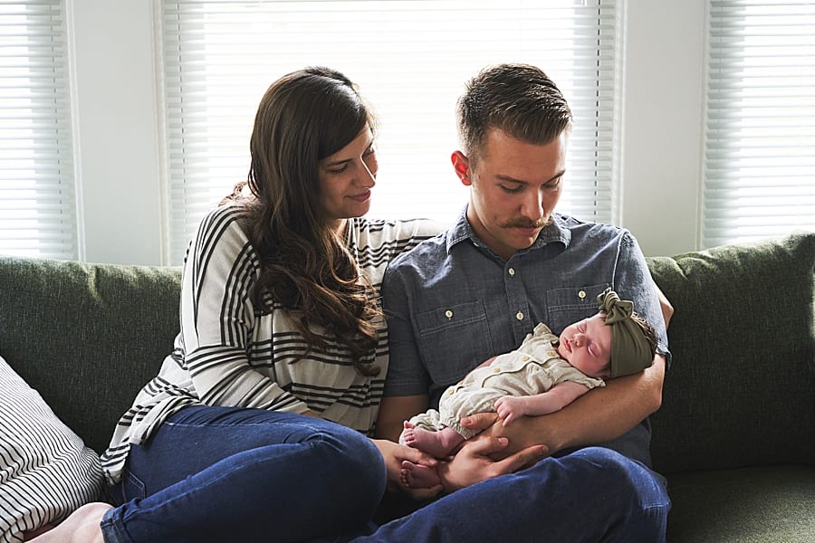 baby on couch with mom and cradled by dad for in home newborn photo session with Mary Beth Miller photography pittsburgh newborn photographer