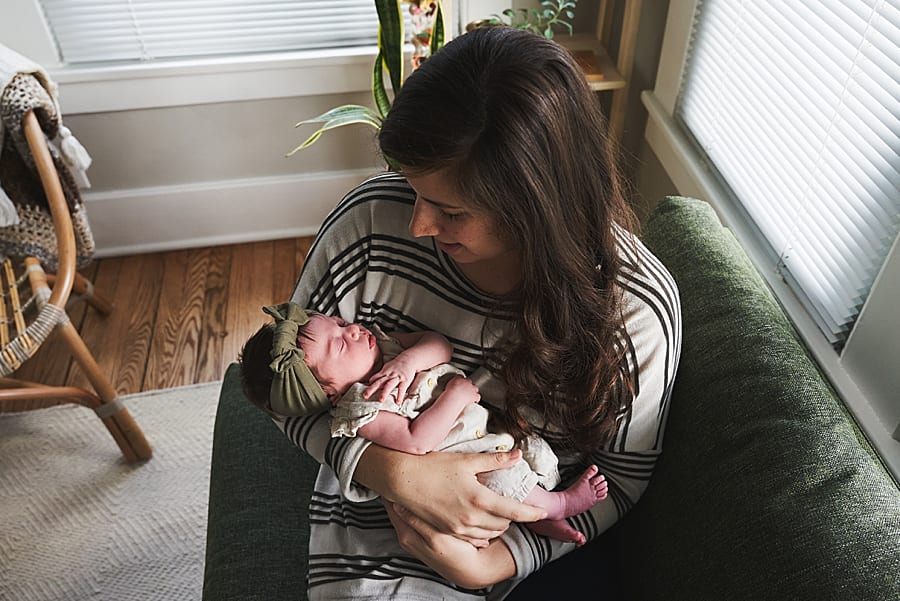 mom cradling baby on couch for in home newborn photo session