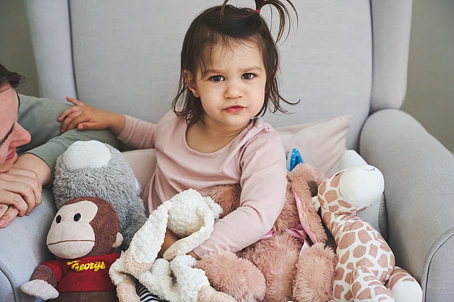 toddler girl in chair in nursery of Shadyside home with stuffed animals