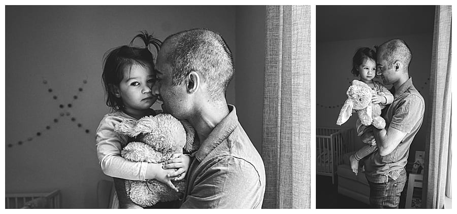 dad holding daughter in window light in black and white