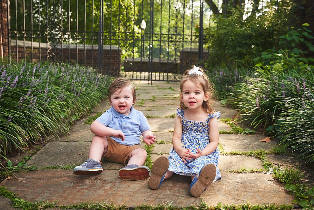 brother and sister during a photo session at the walled garden in Mellon Park with black metal gates and brick walls and flowers
