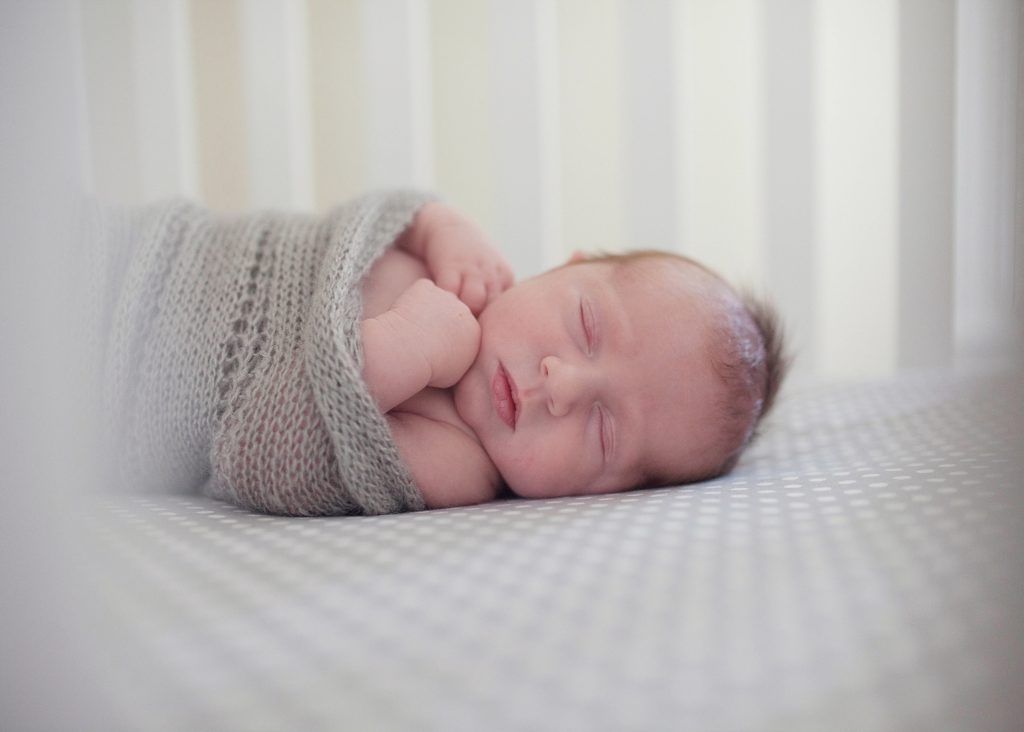  swaddled sleeping baby on bed how to take the best photos of your newborn baby