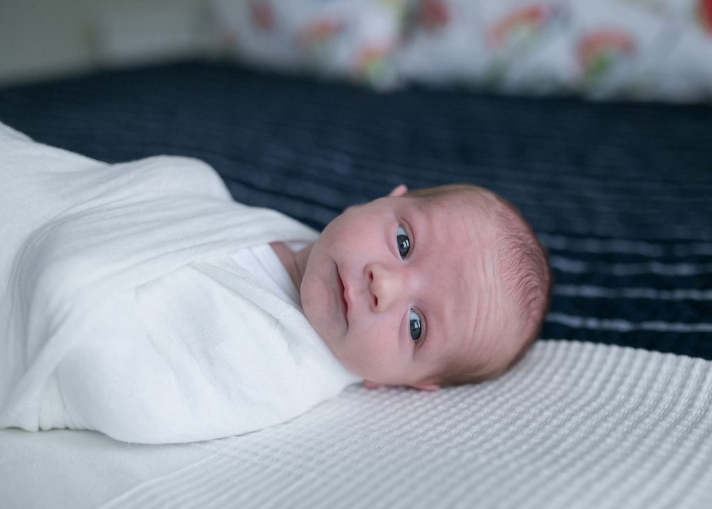  swaddled awake baby on bed how to take the best photos of your newborn baby