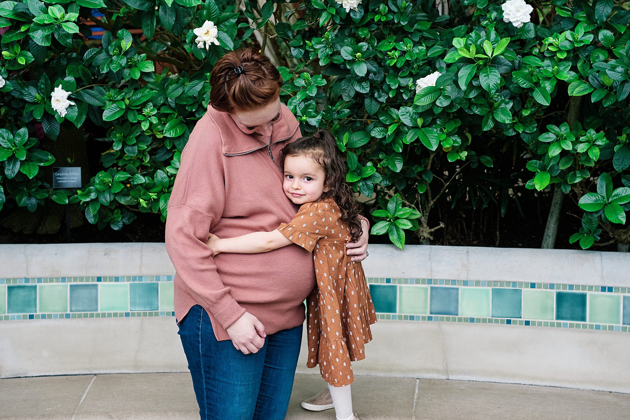girl hugging pregnant mom at Phipps conservatory in pittsburgh for family photo session 