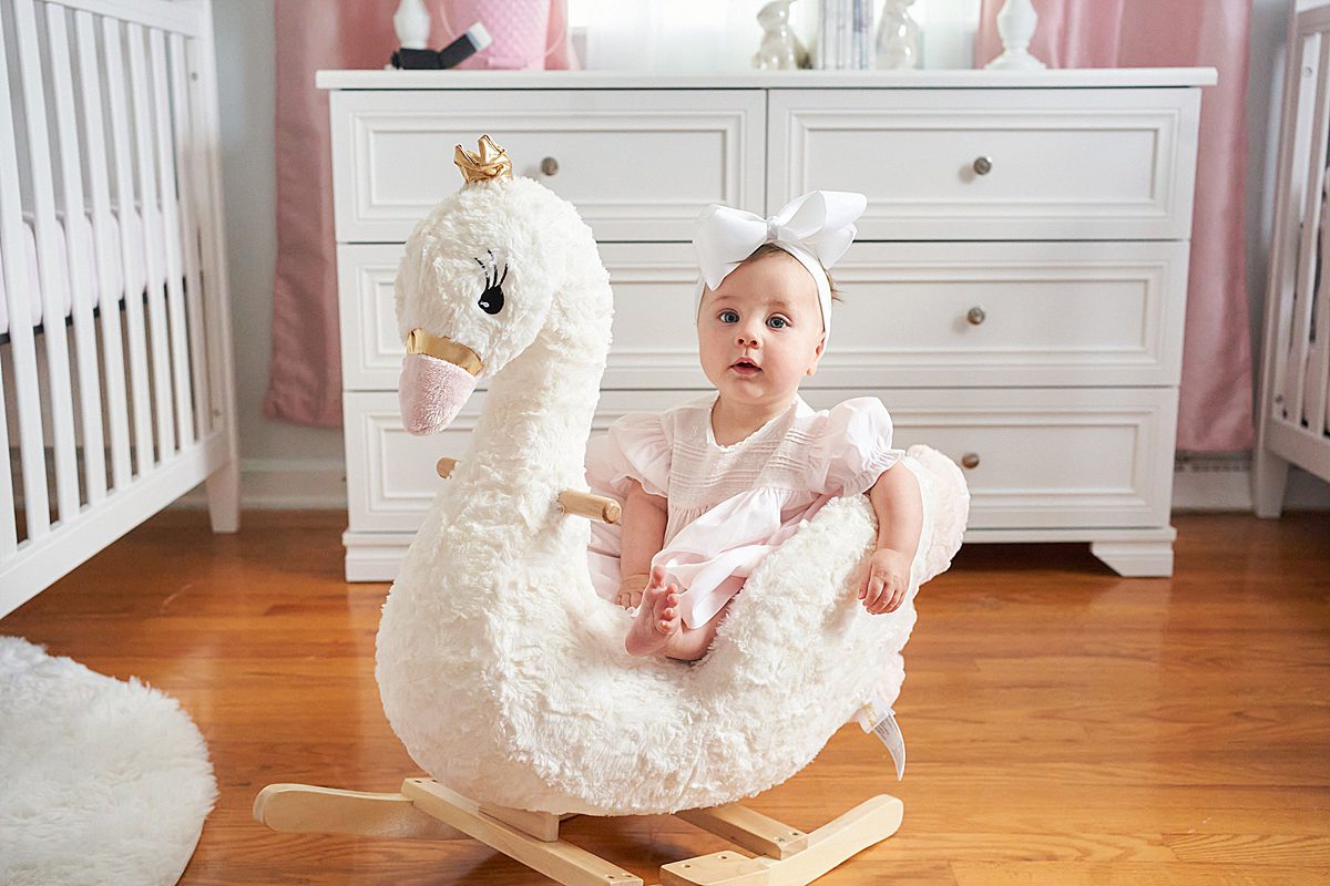 baby girl on swan rocker in nursery for family session in upper saint clair