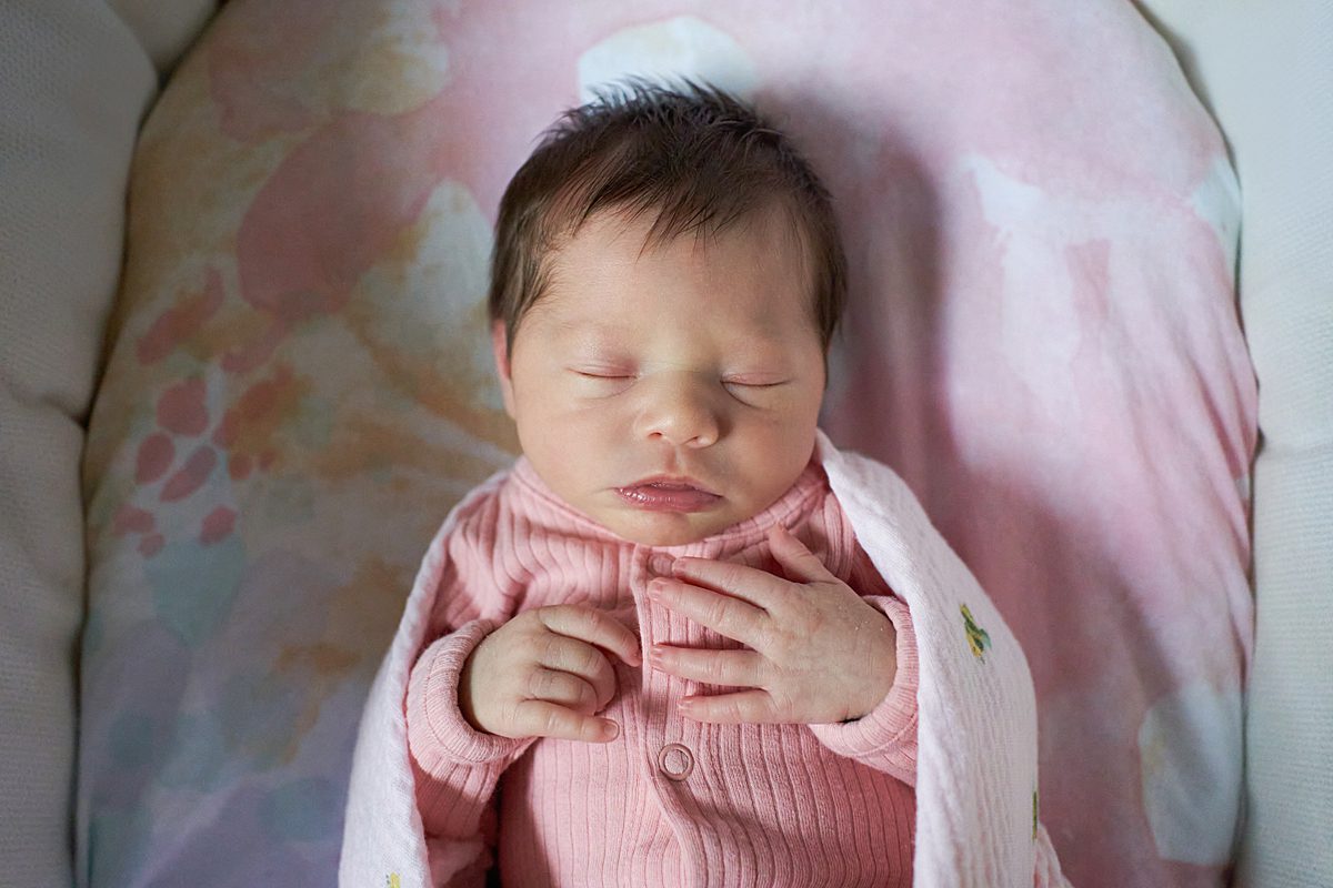  baby girl in pink sleeper sleeping in a bassinet seven fields newborn photographer 