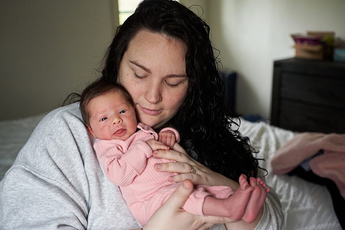 seven fields newborn photographer mom holding baby girl in pink 
