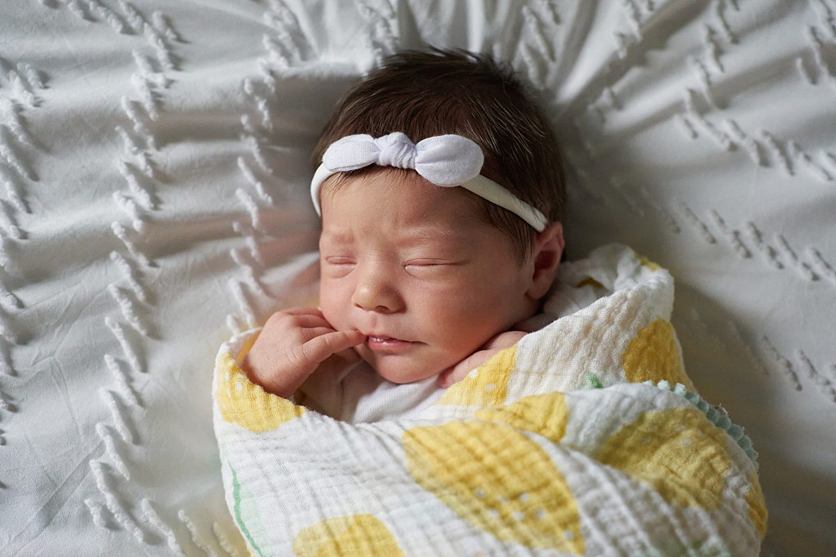 baby girl sleeping for newborn photo session seven fields wrapped in a lemon print blanket with a white bow