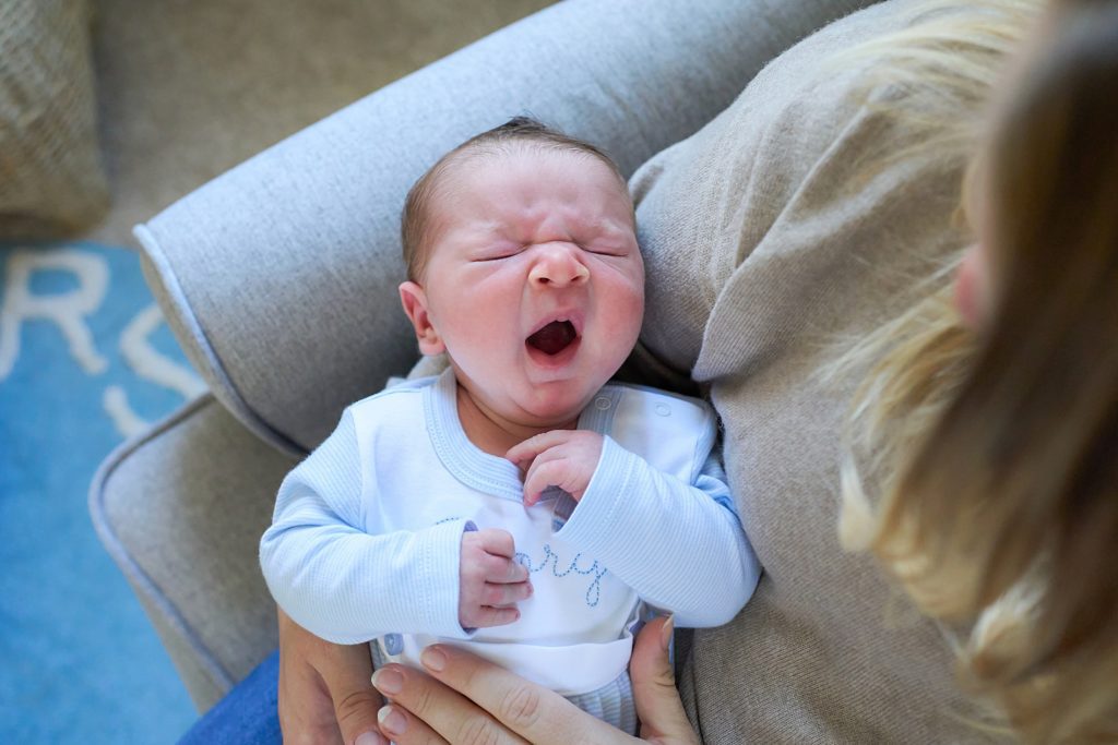 yawing newborn infant in moms arms