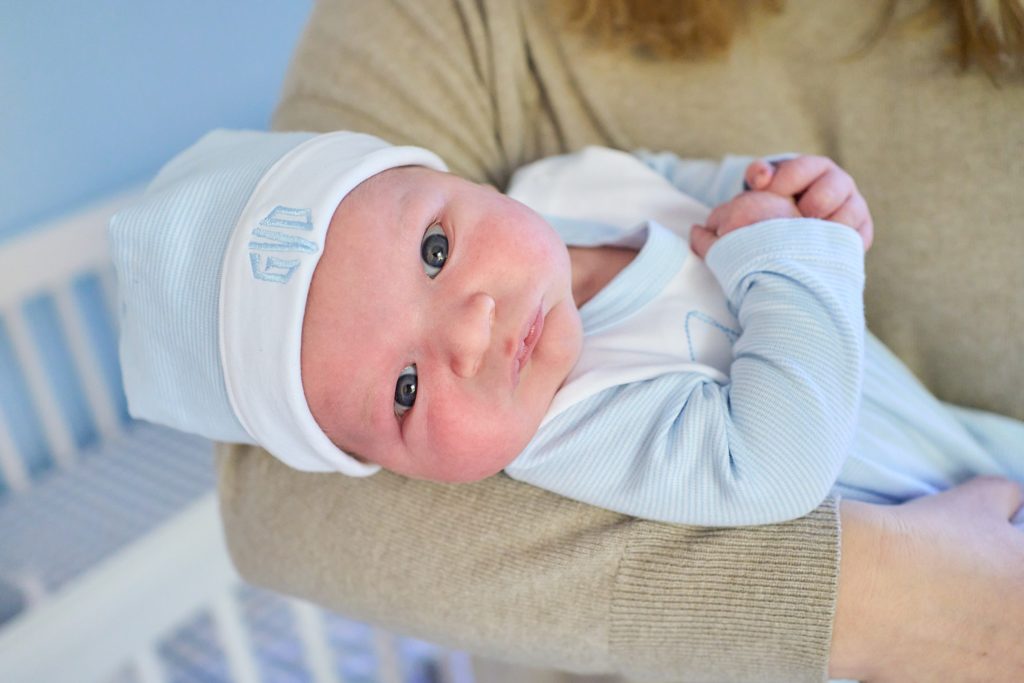 newborn baby with hat awake looking at camera