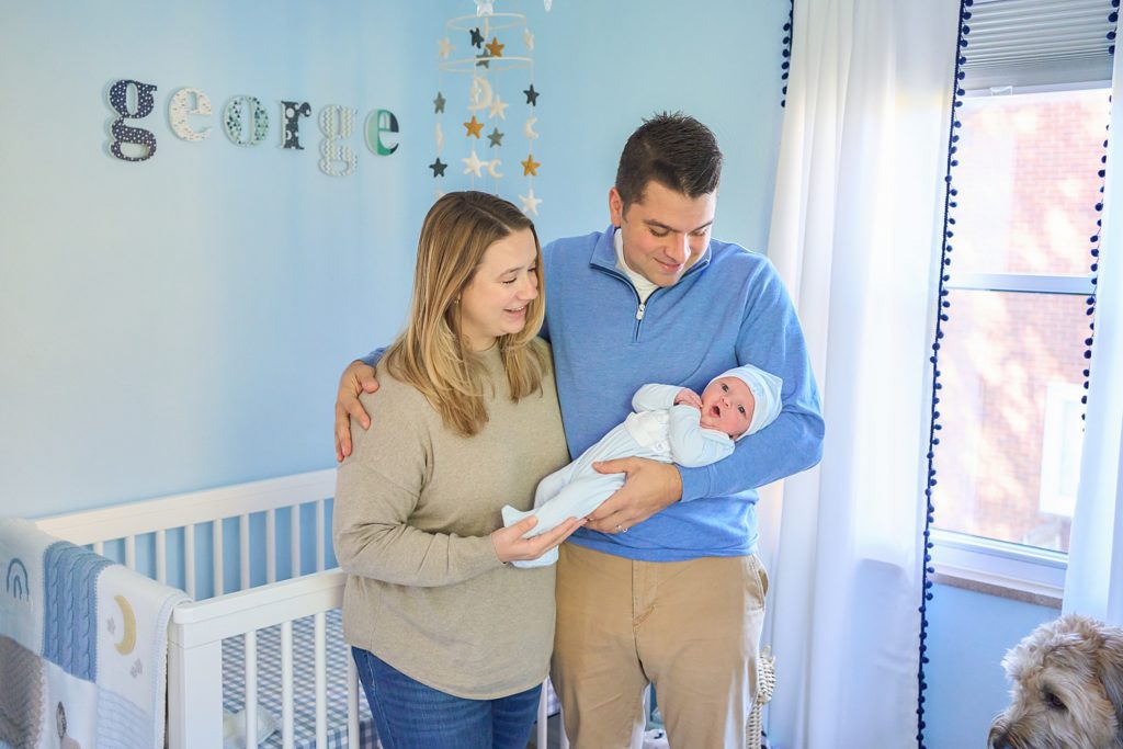 mom dad and newborn baby with dog in nursery at mccandless area home