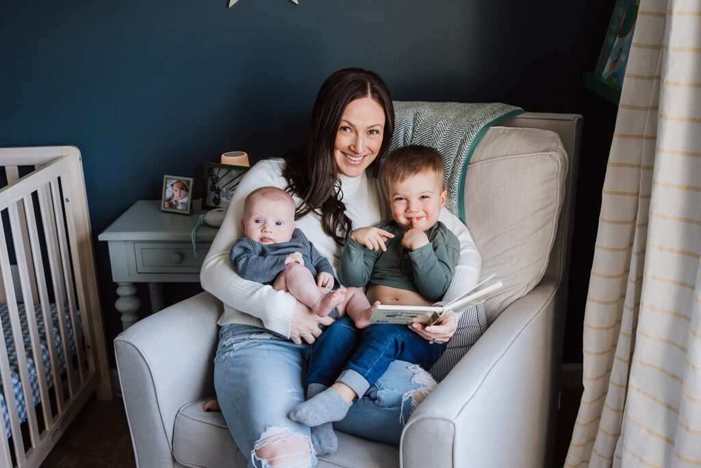 mom, baby and toddler reading a book in nursery of wexford home for a family photo session 
