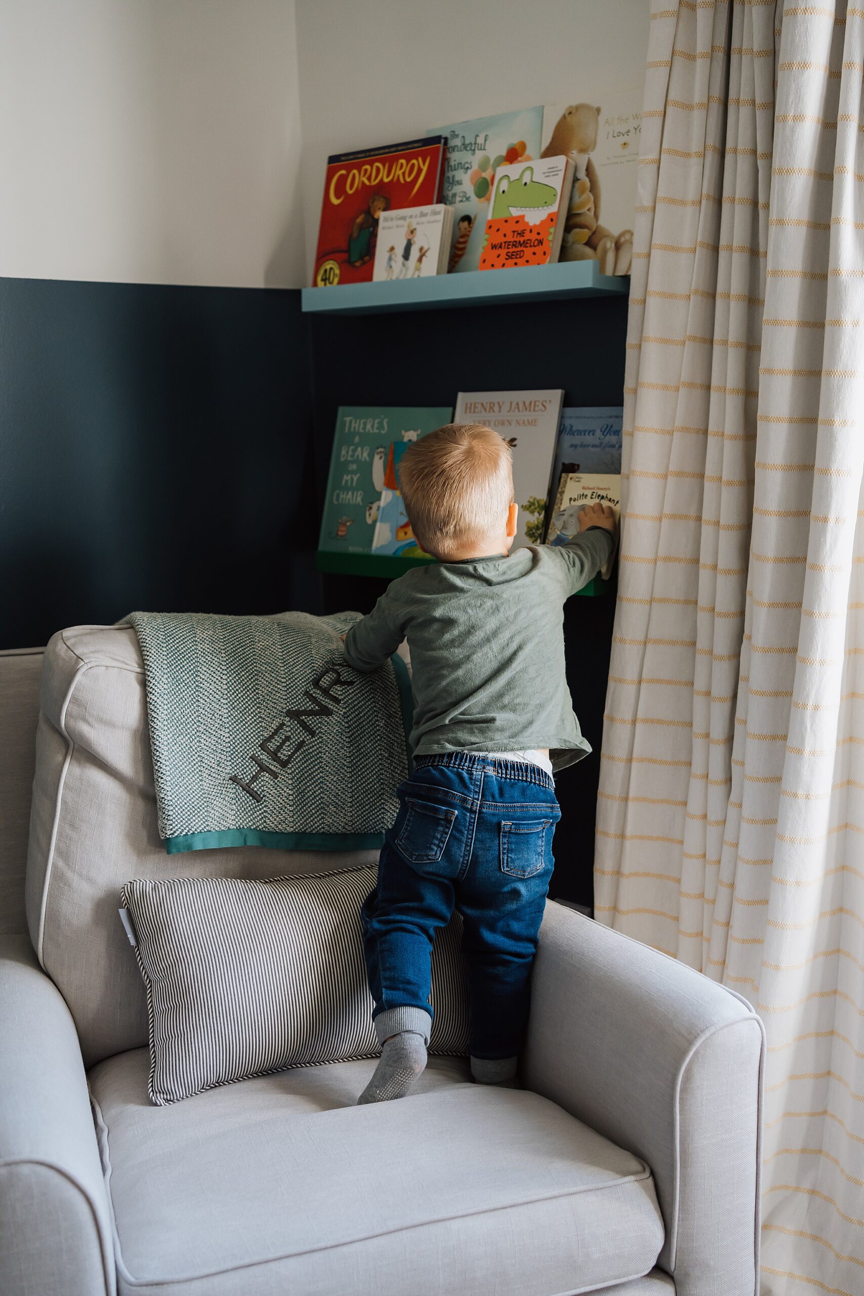 toddler standing on chair to reach a book