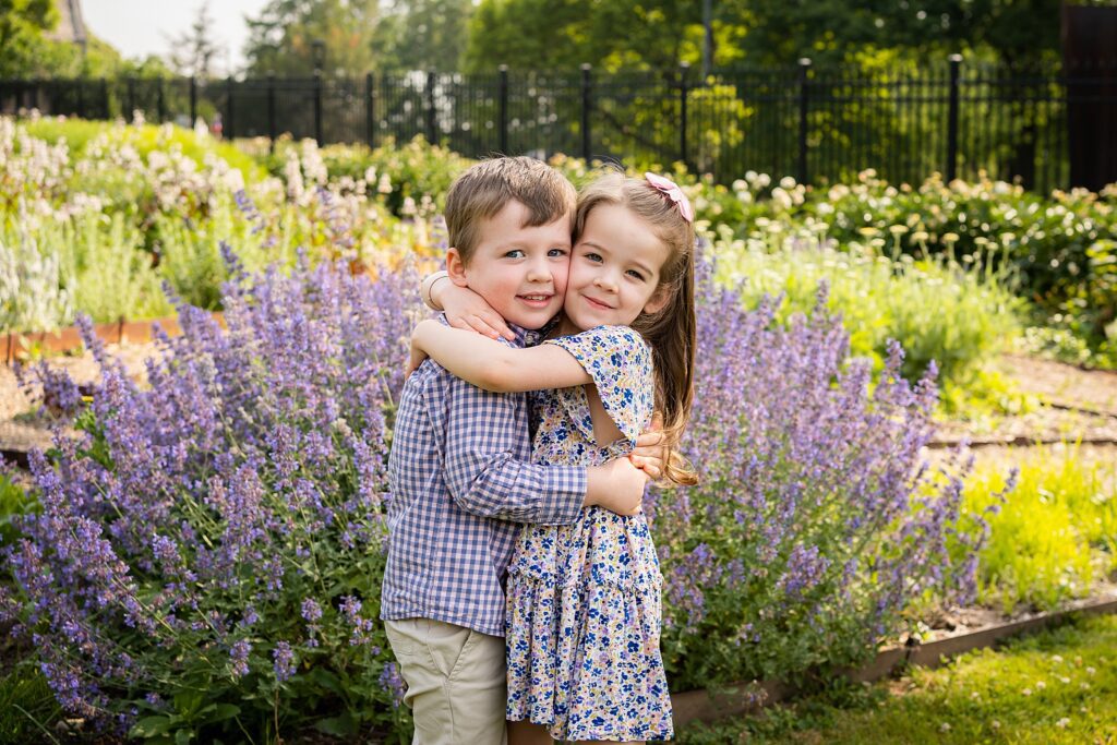 boy and girl embracing for a photo in the flower garden of hartwood acres mansion for a family photo session