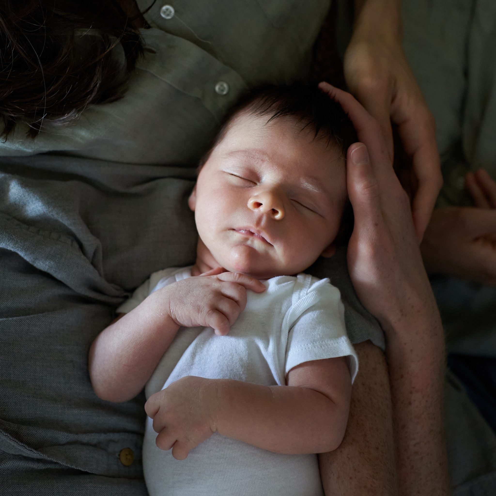 closeup of newborn baby sleeping in dads arms