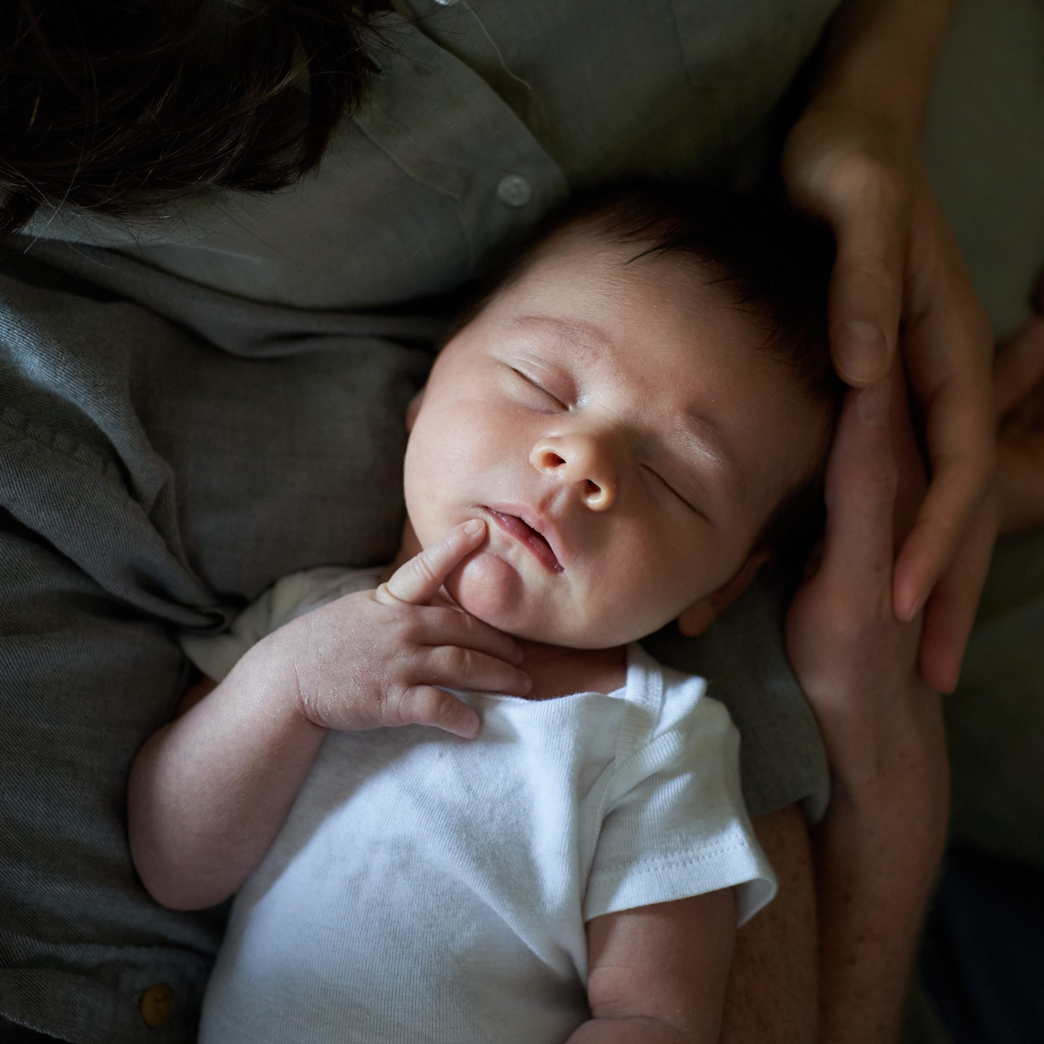 closeup of newborn baby sleeping in dads arms