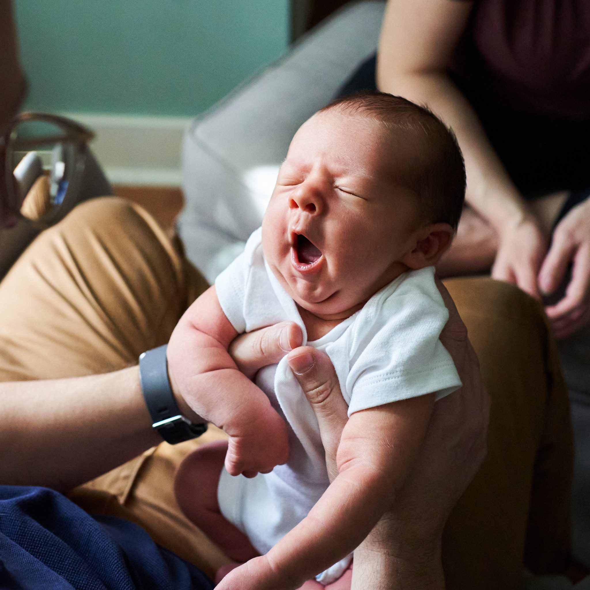 baby with eyes closed in white onesie yawning