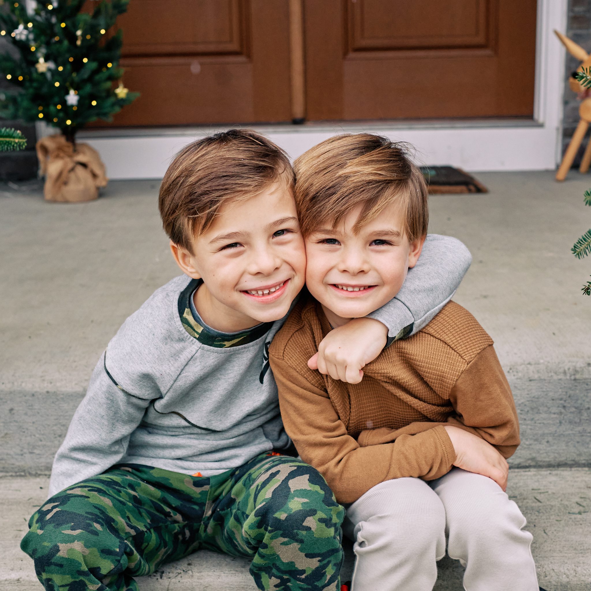 two brother embracing and sitting on front porch steps together looking at the camera
