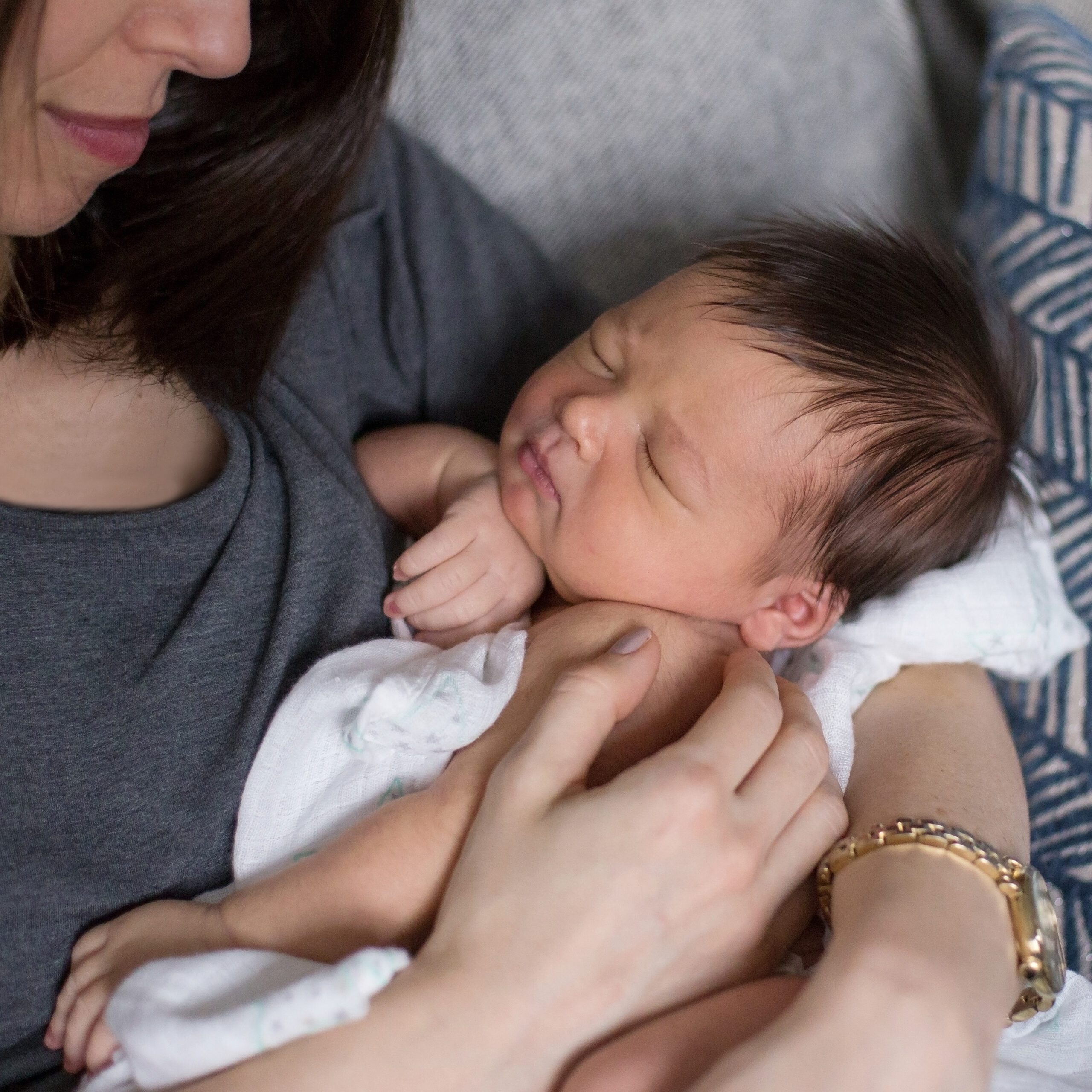newborn baby with lots of brown hair being cradled by mom