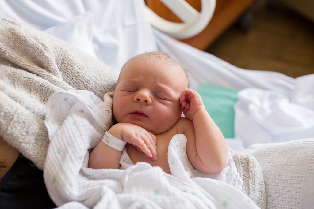 A newborn baby sleeping in a hospital bed.