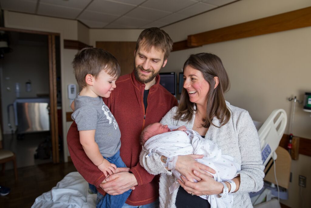 A family holding a newborn in a hospital room.