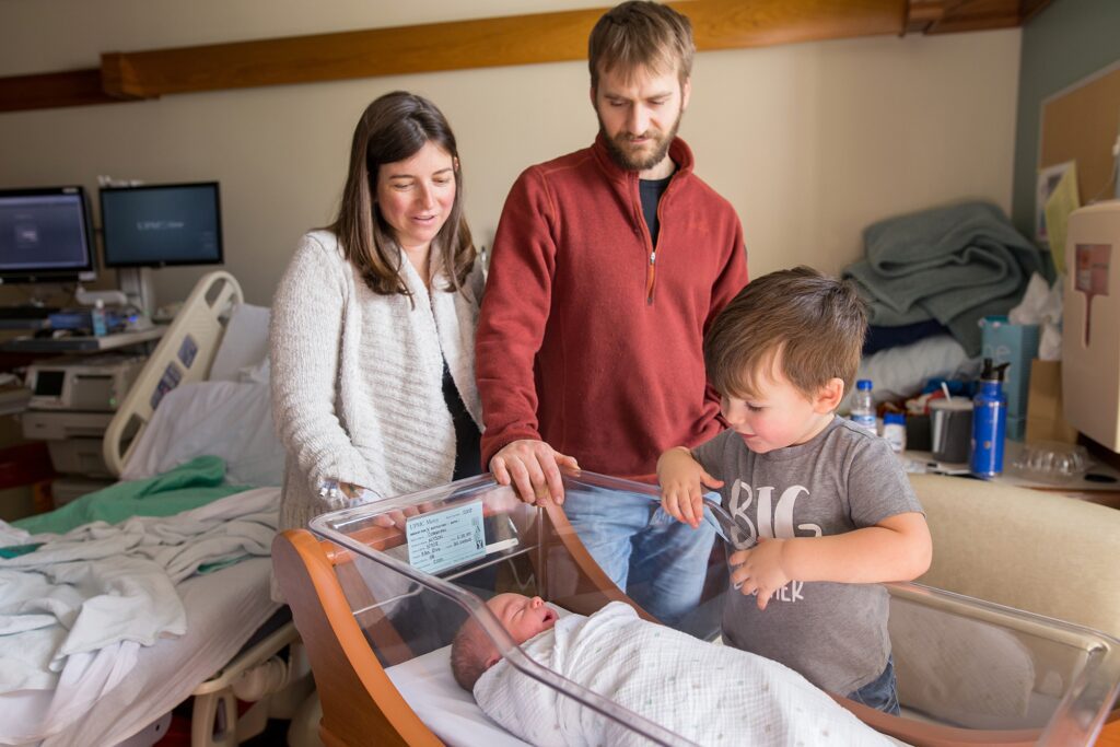 A family is looking at a newborn in a hospital room.