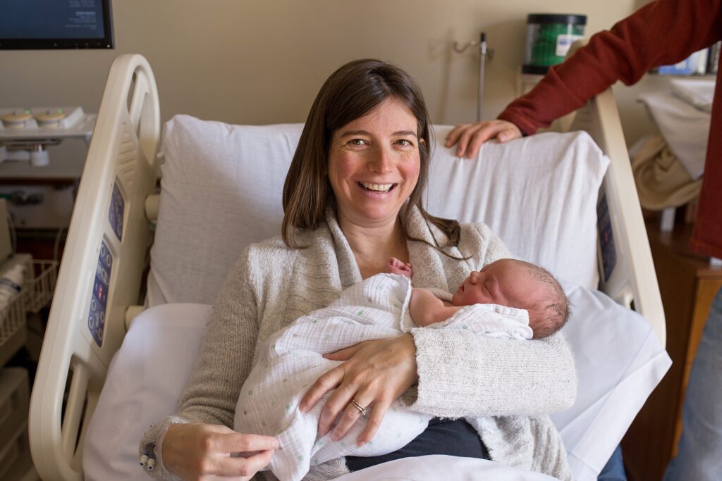 A woman holding a baby in a hospital bed.