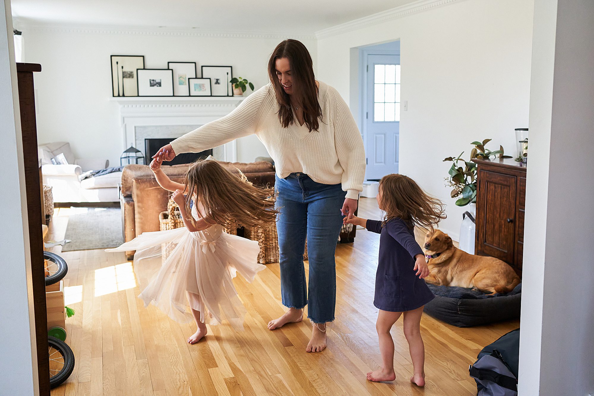 A mother and her two daughters dancing in their living room.