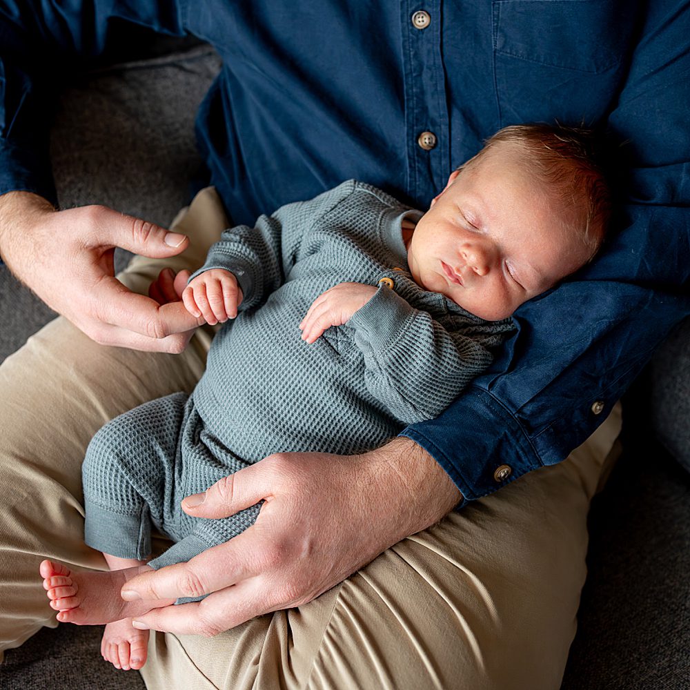 baby held by dad with his little hand holding dads