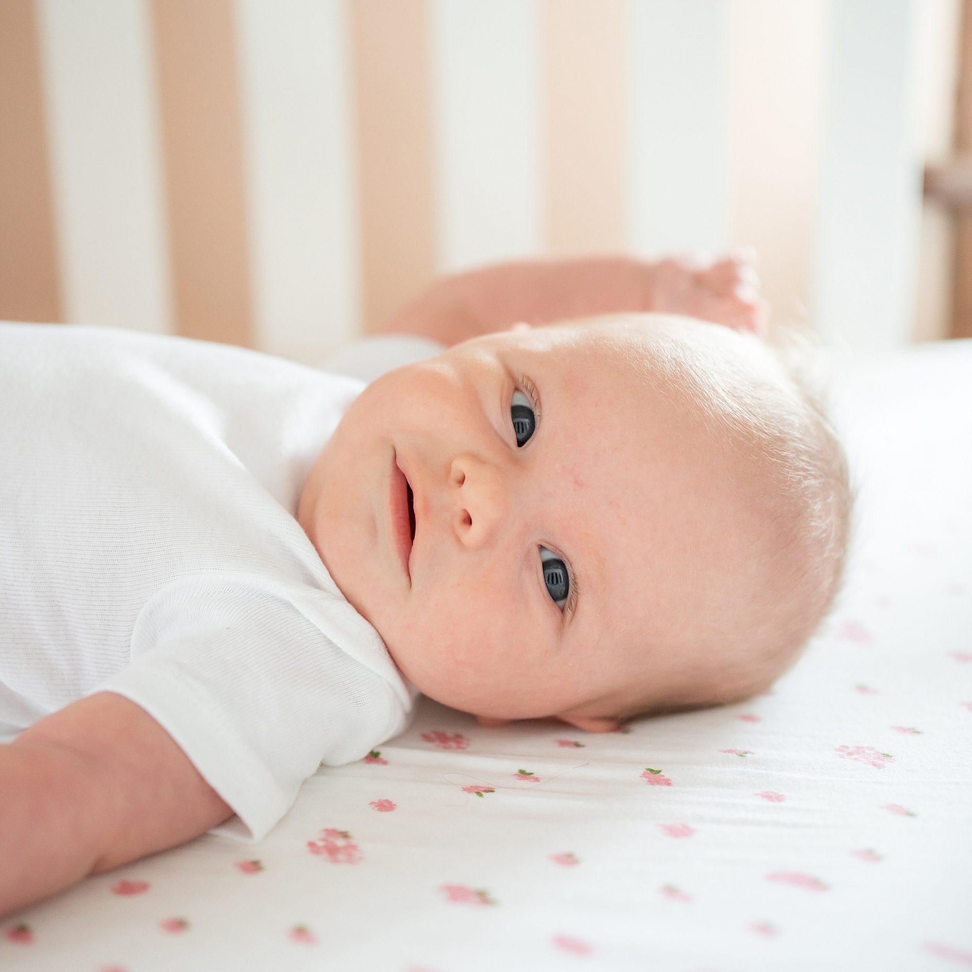 A baby is laying in a crib with his eyes wide open.