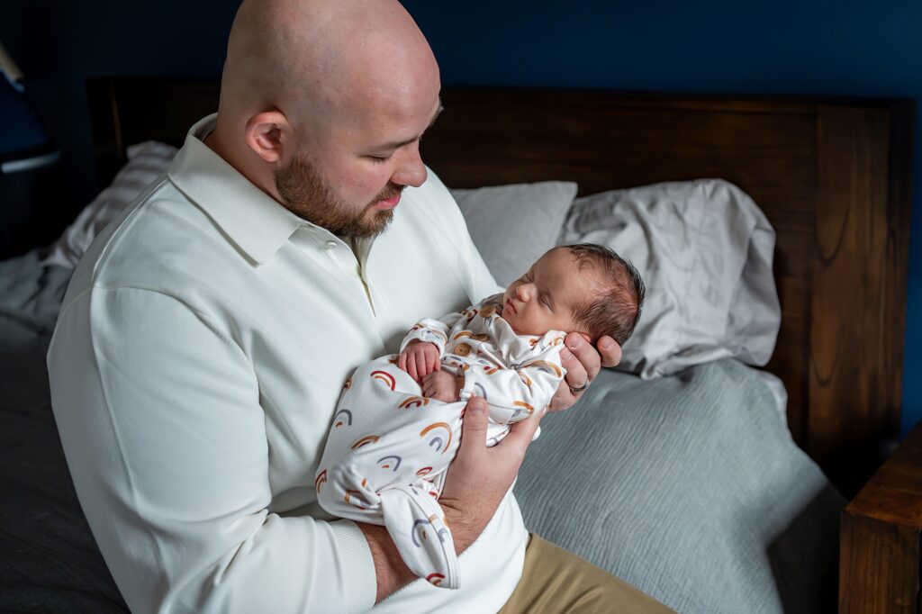 A man holding a baby on a bed.
