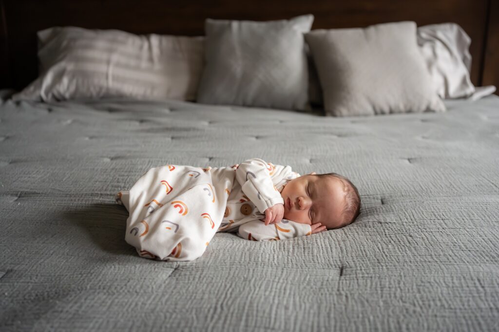 A newborn baby sleeping on a bed.