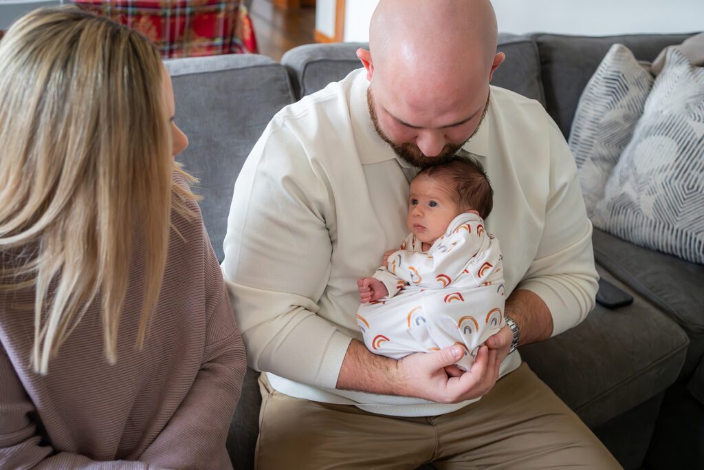 A man and woman holding a baby on a couch.