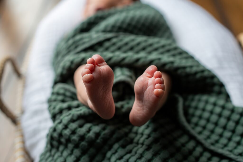A baby's feet laying in a green blanket.