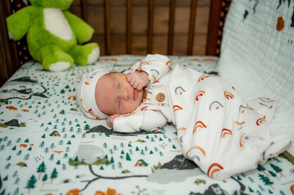A baby sleeping in a crib with a teddy bear.