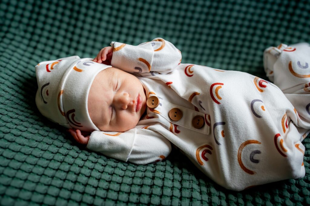 A newborn baby sleeping on a green blanket.