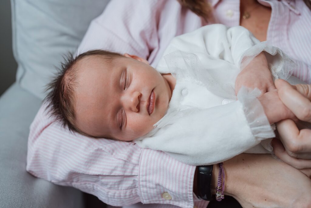 Sleeping newborn cradled in a newborn photographer's arms.