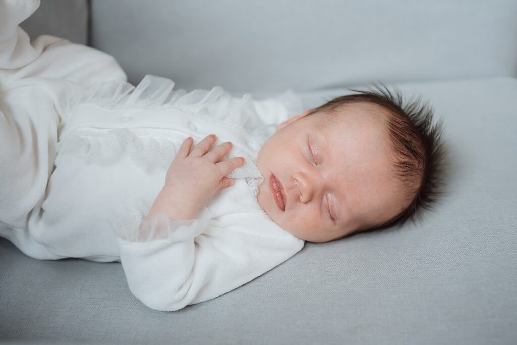 Newborn baby sleeping peacefully in white clothing, captured by a newborn photographer.