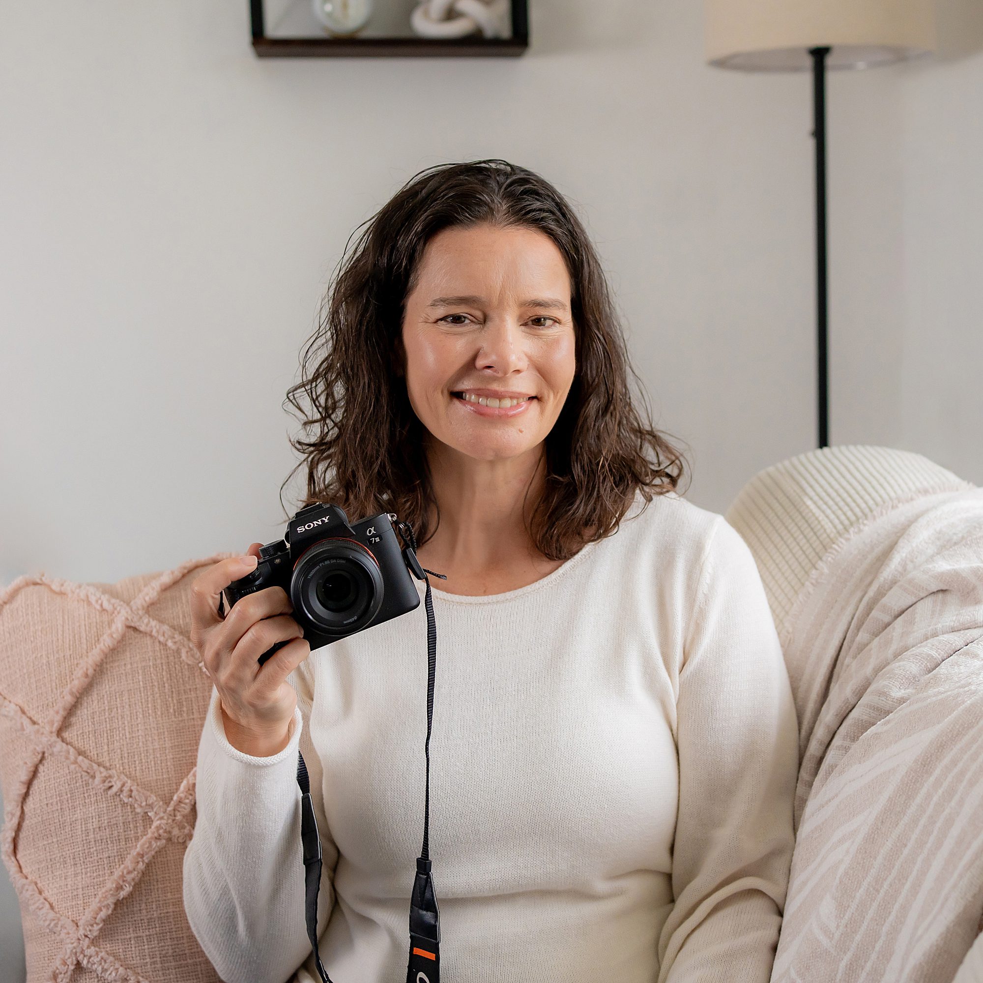 A woman sitting on a couch holding a camera.