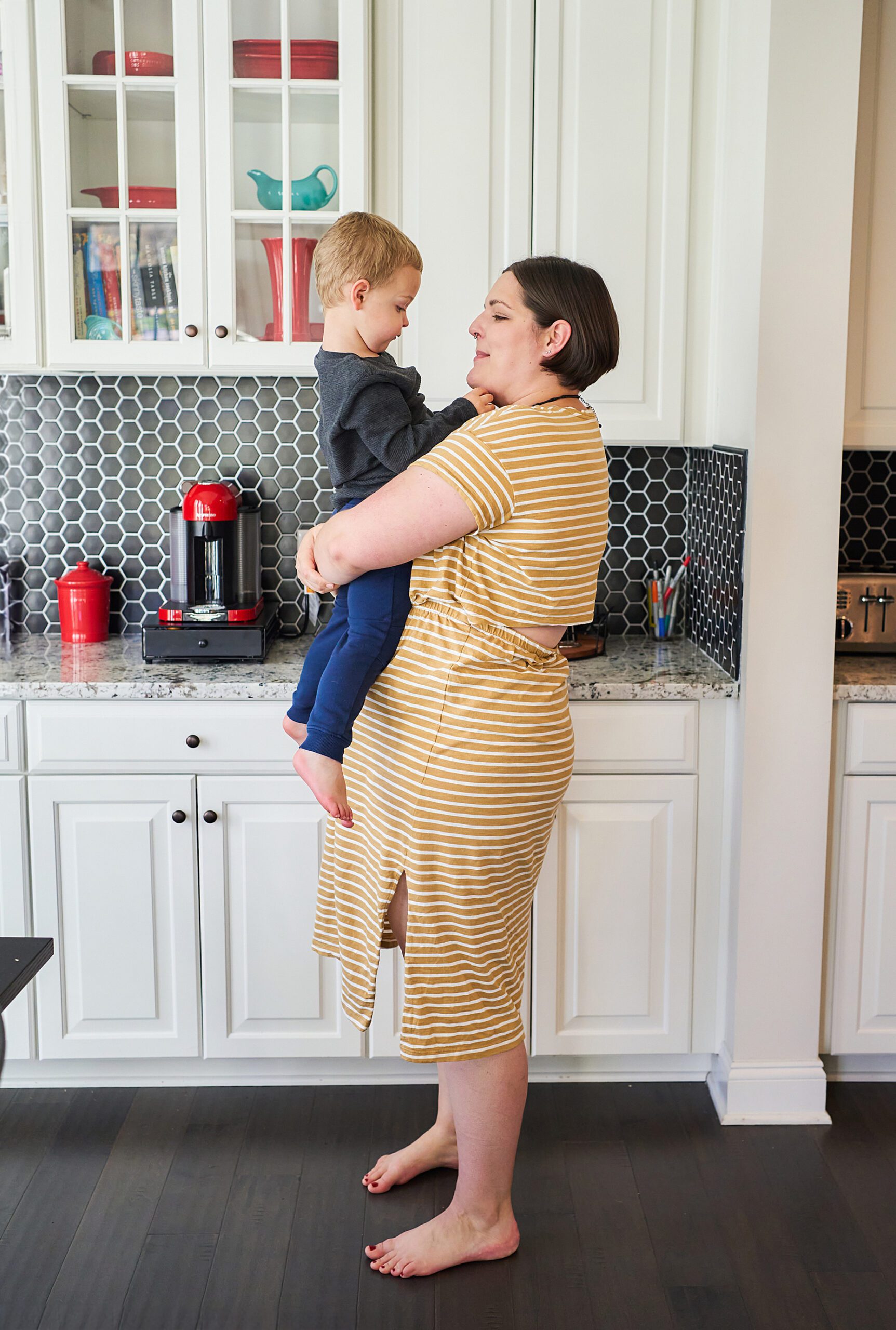 A mother holding her young son in a modern kitchen.