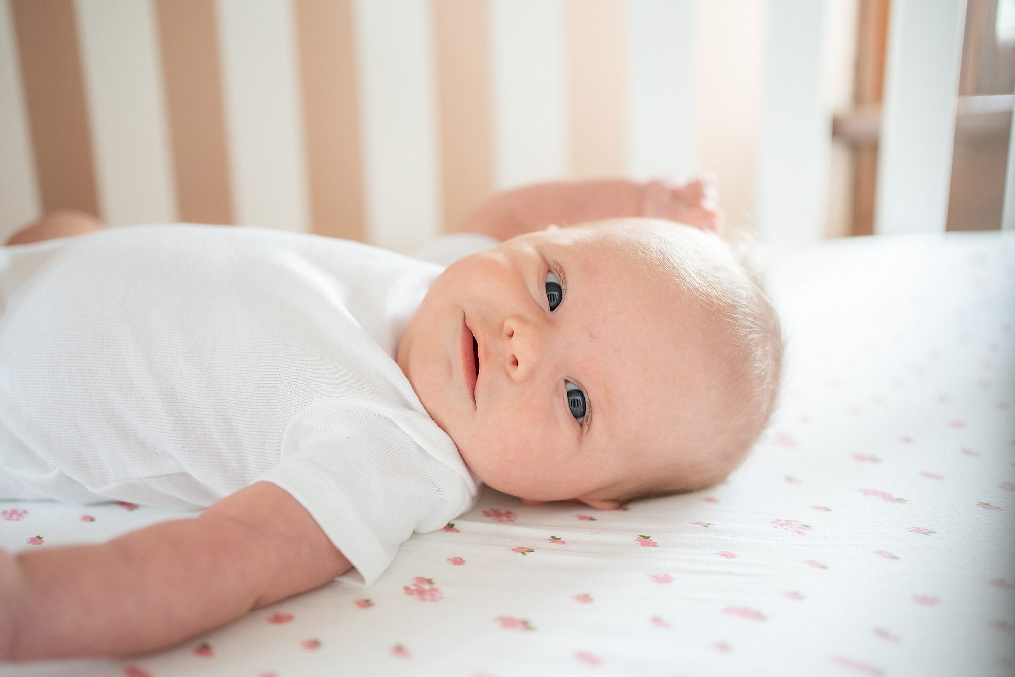 Baby lying on a patterned sheet in a crib.