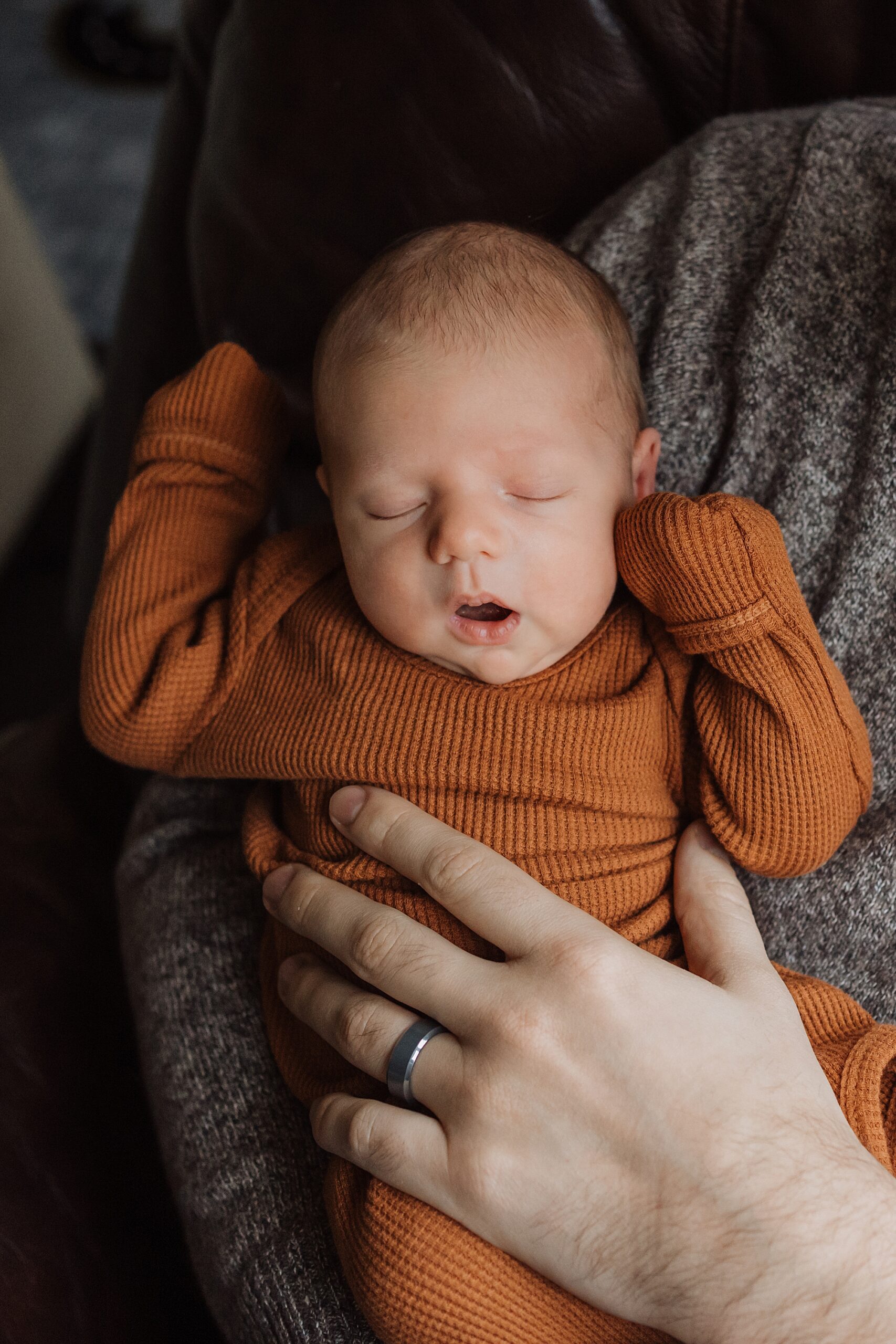 A sleeping newborn cradled in an adult's hands.