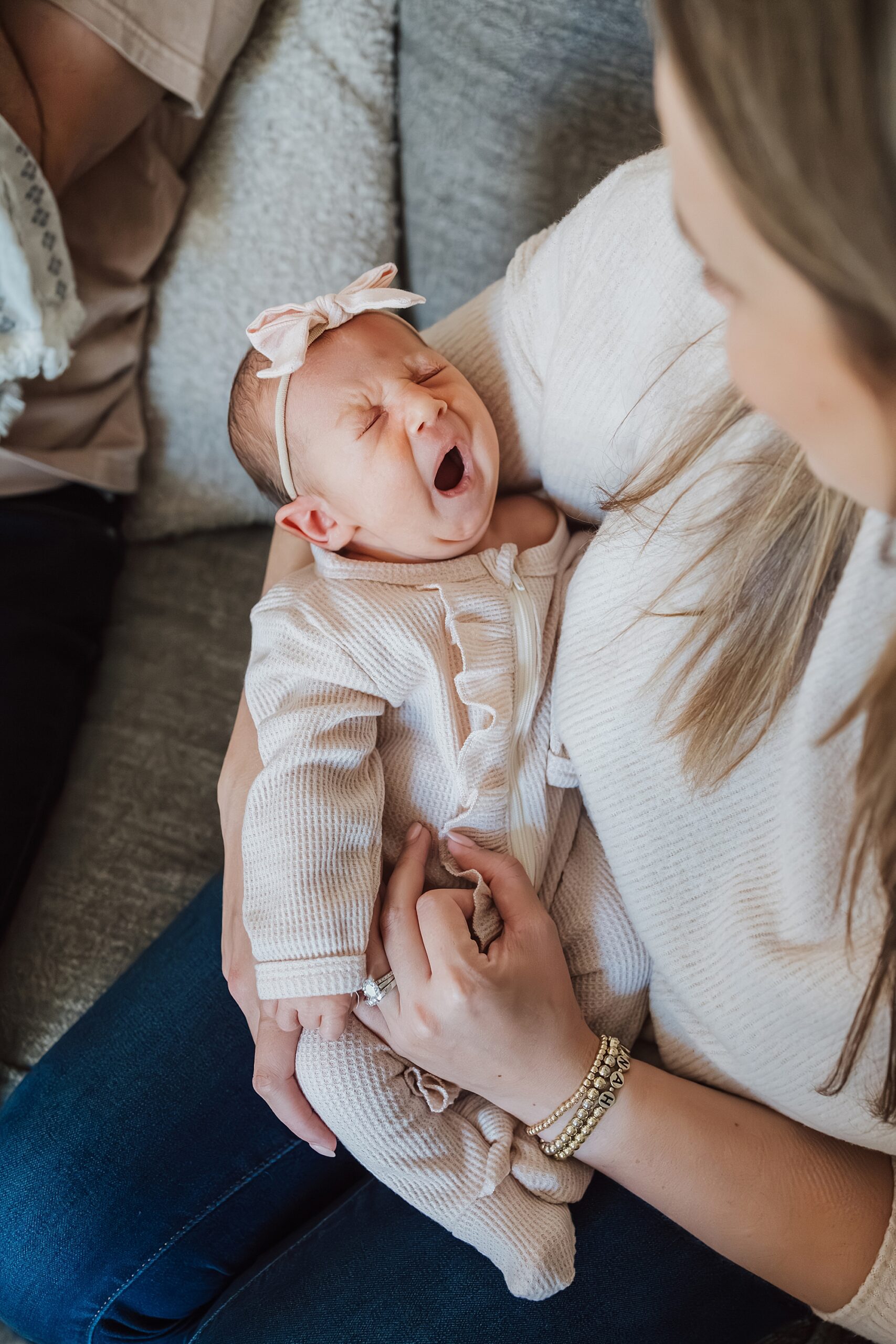A baby yawning while being cradled in a woman's arms.